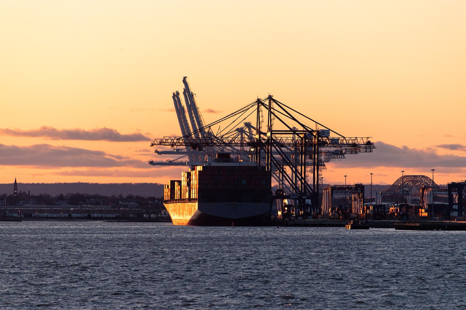 Container vessel leaving port at sunset